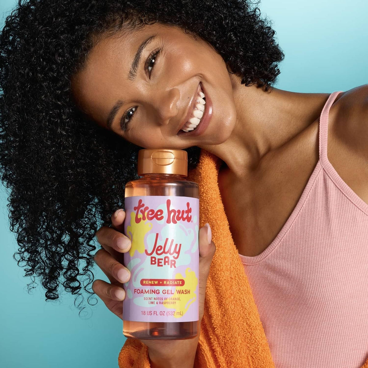 Orange foaming gel body wash bottle held by smiling woman with towel