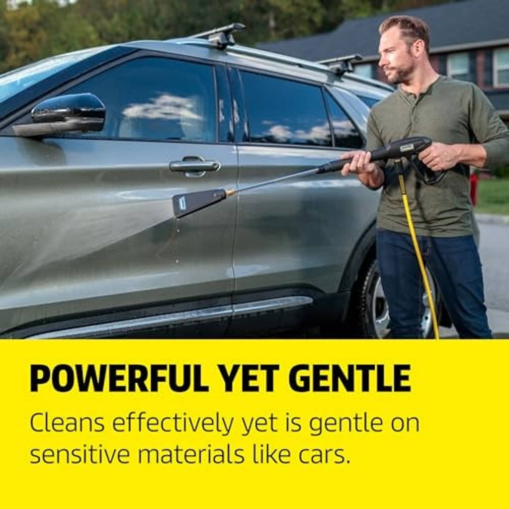 Pressure washer nozzle held by a person, spraying water toward a car exterior