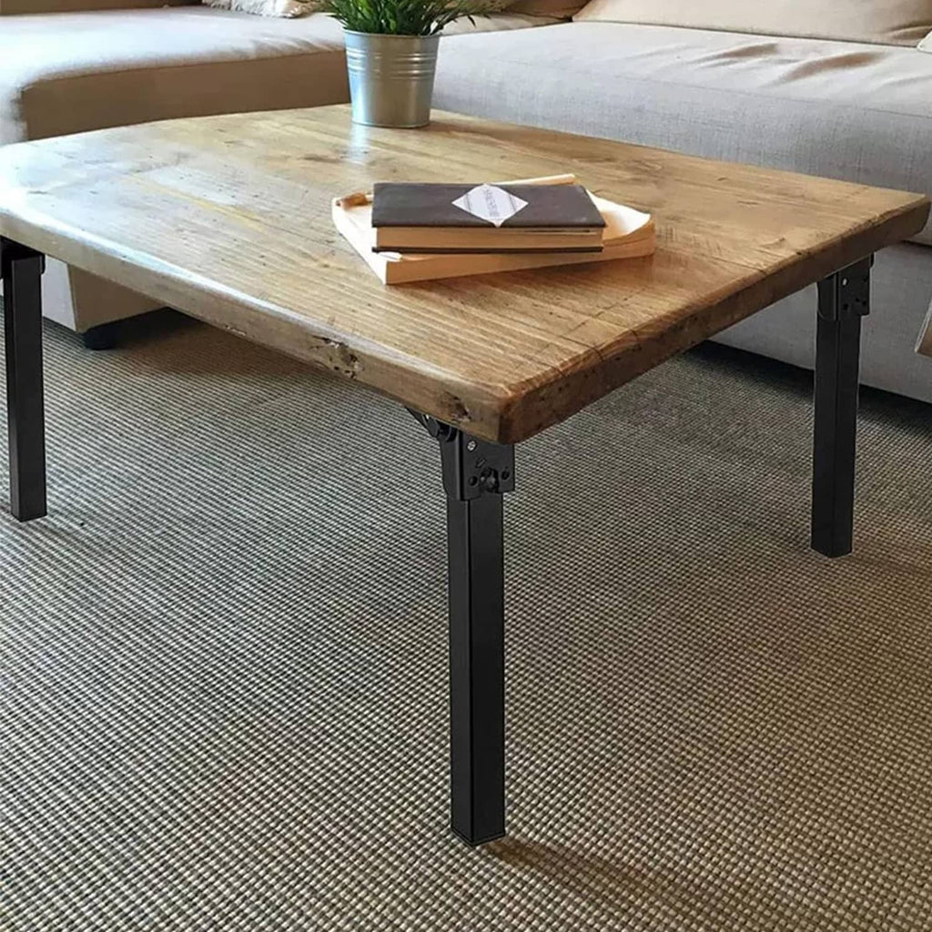 Black metal folding table legs with hinge joints under a wooden table