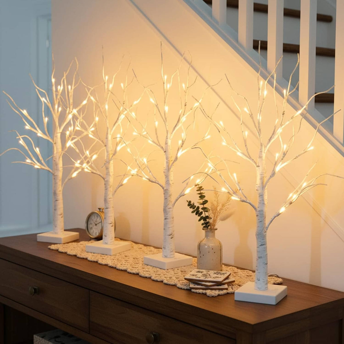 Set of lighted birch tree decorations with white trunks and warm LEDs on display