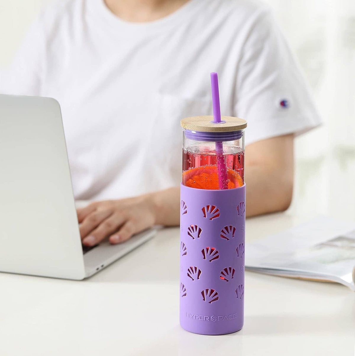 Purple glass tumbler with silicone sleeve, bamboo lid, straw, and orange fruit pieces