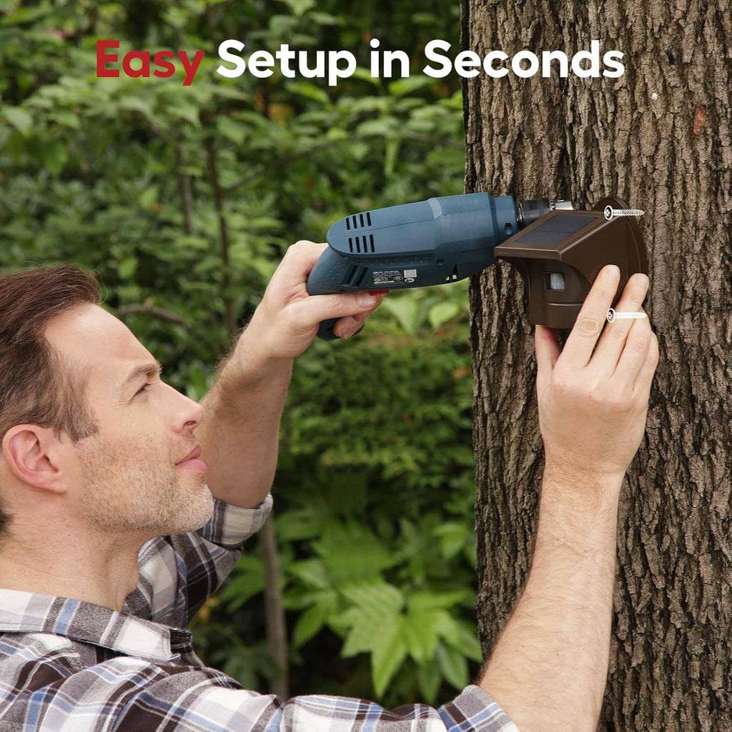 Driveway alarm sensor setup with installer hands mounting it to a tree