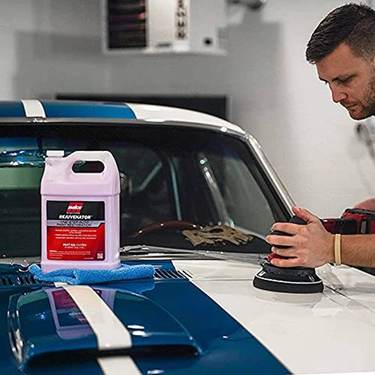 Auto paint restoration bottle with blue cloth and polishing pad on car hood