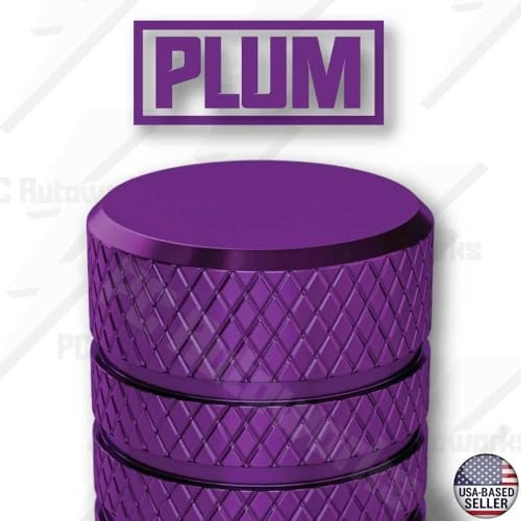 Plum purple tire valve stem cap close-up, textured sides with a smooth flat top