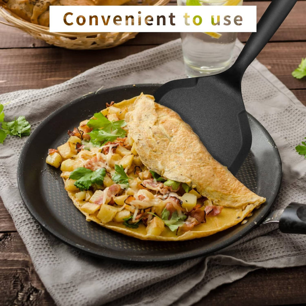 Black silicone pancake flipper lifting omelet in a nonstick pan