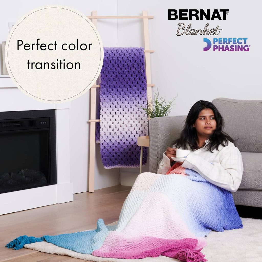 Crocheted throw blanket in purple with light blue and pink sections, fringe edges
