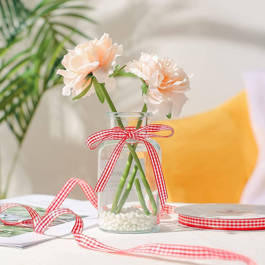 Red and white gingham ribbon tied around vase flowers, thin striped ribbon with loose end