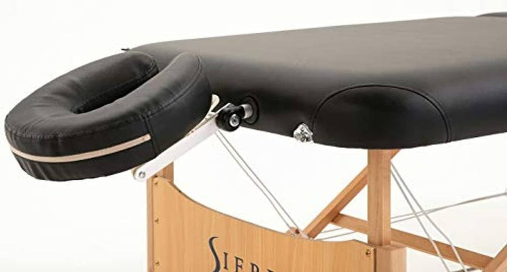 Black massage table cushion on wooden frame with support knobs and straps