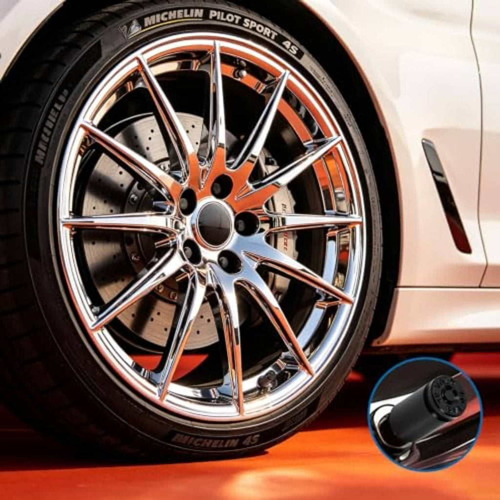 Black valve stem caps with bullet-style design near a car wheel, 1 cap highlighted