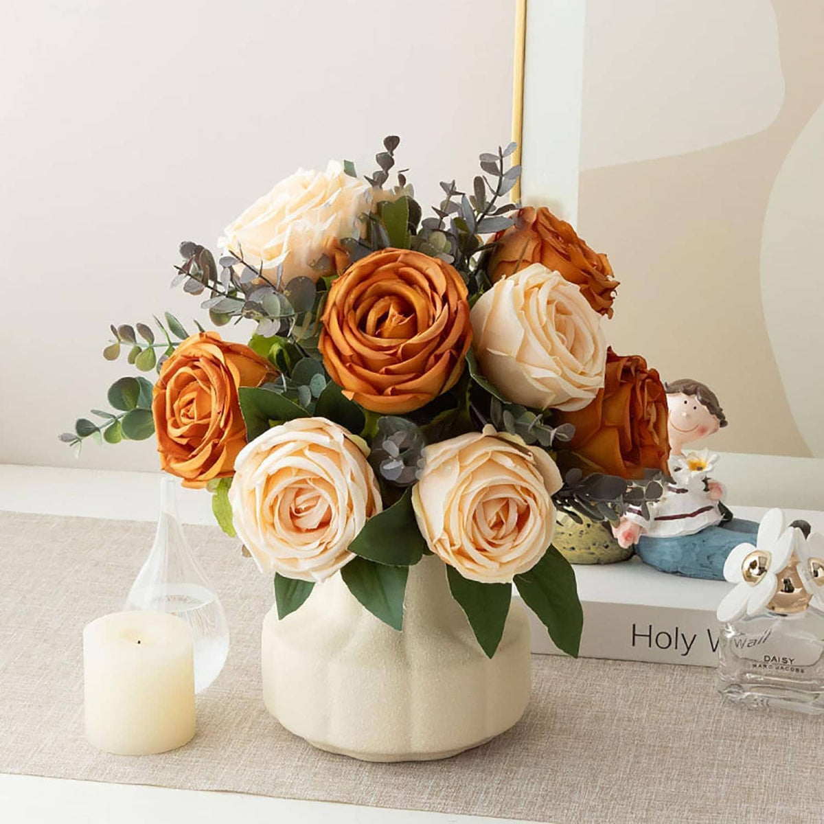 Artificial rose bouquet in cream vase with orange and white roses, green leaves, and bird figurine