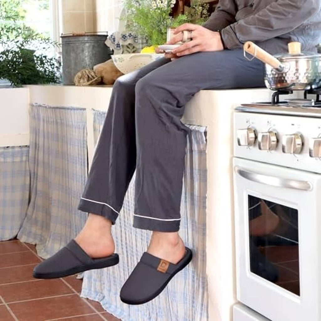 Men wearing dark gray slip-on slippers with cushioned plush lining in a kitchen setting