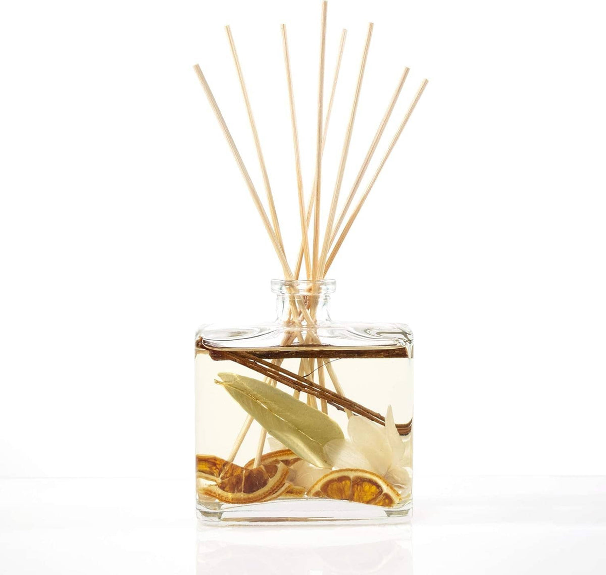 Clear reed diffuser bottle with tan reeds and visible citrus slices inside