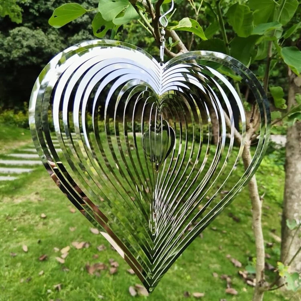 Heart garden wind chime spinner hanging on a branch, reflective silver spiral blades