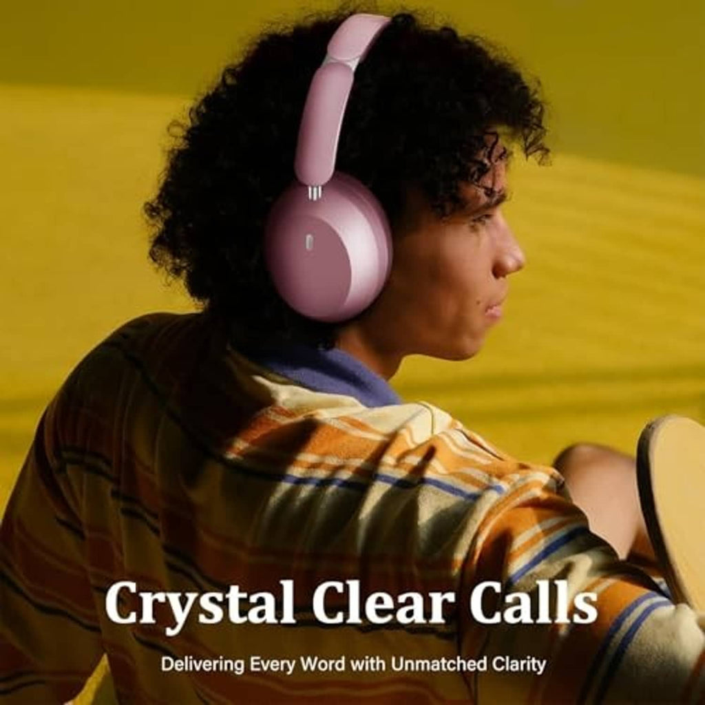 Pink over-ear wireless headphones worn by a person over curly hair