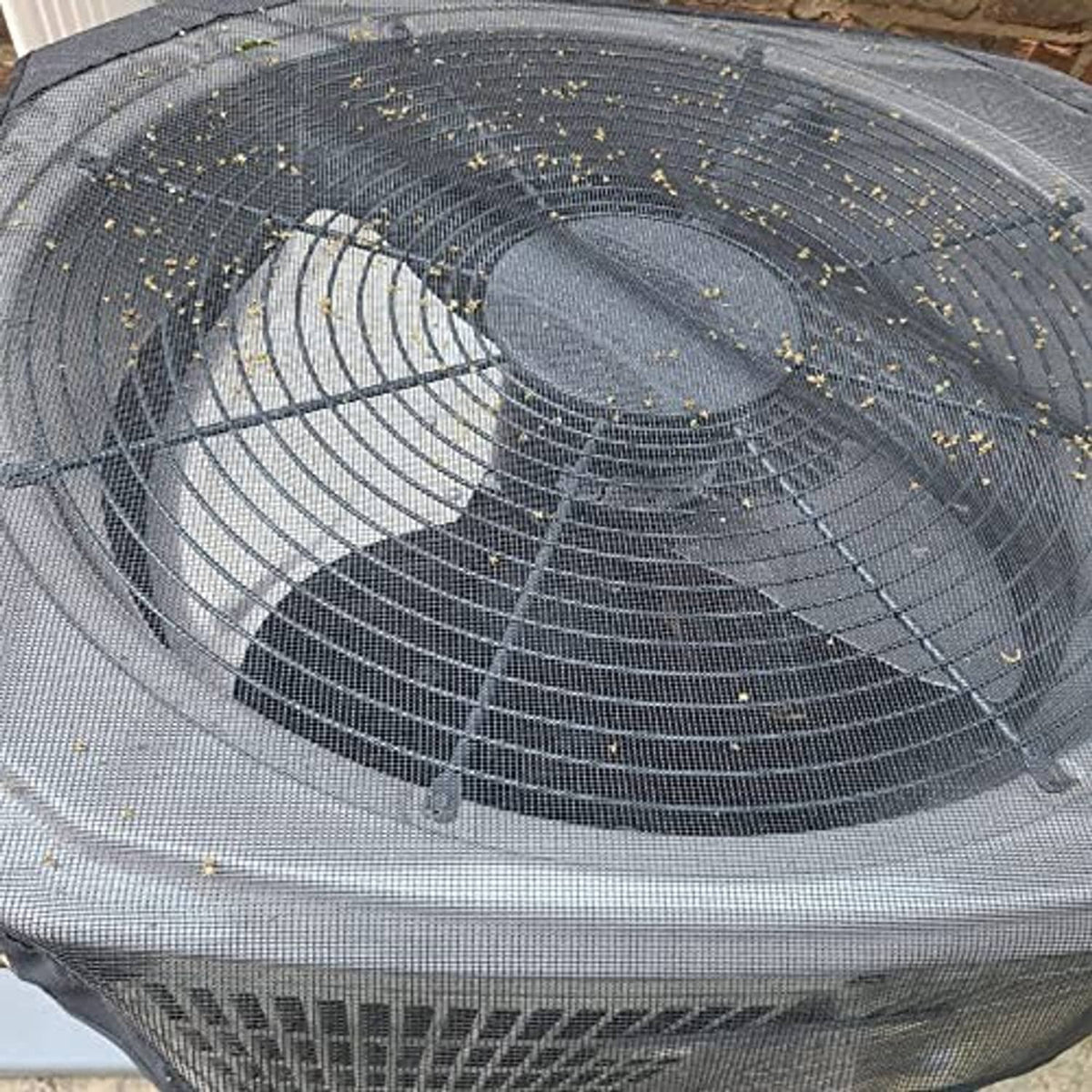 Outdoor AC cover close-up: gray top mesh with leaf speckles and elastic edge seam.