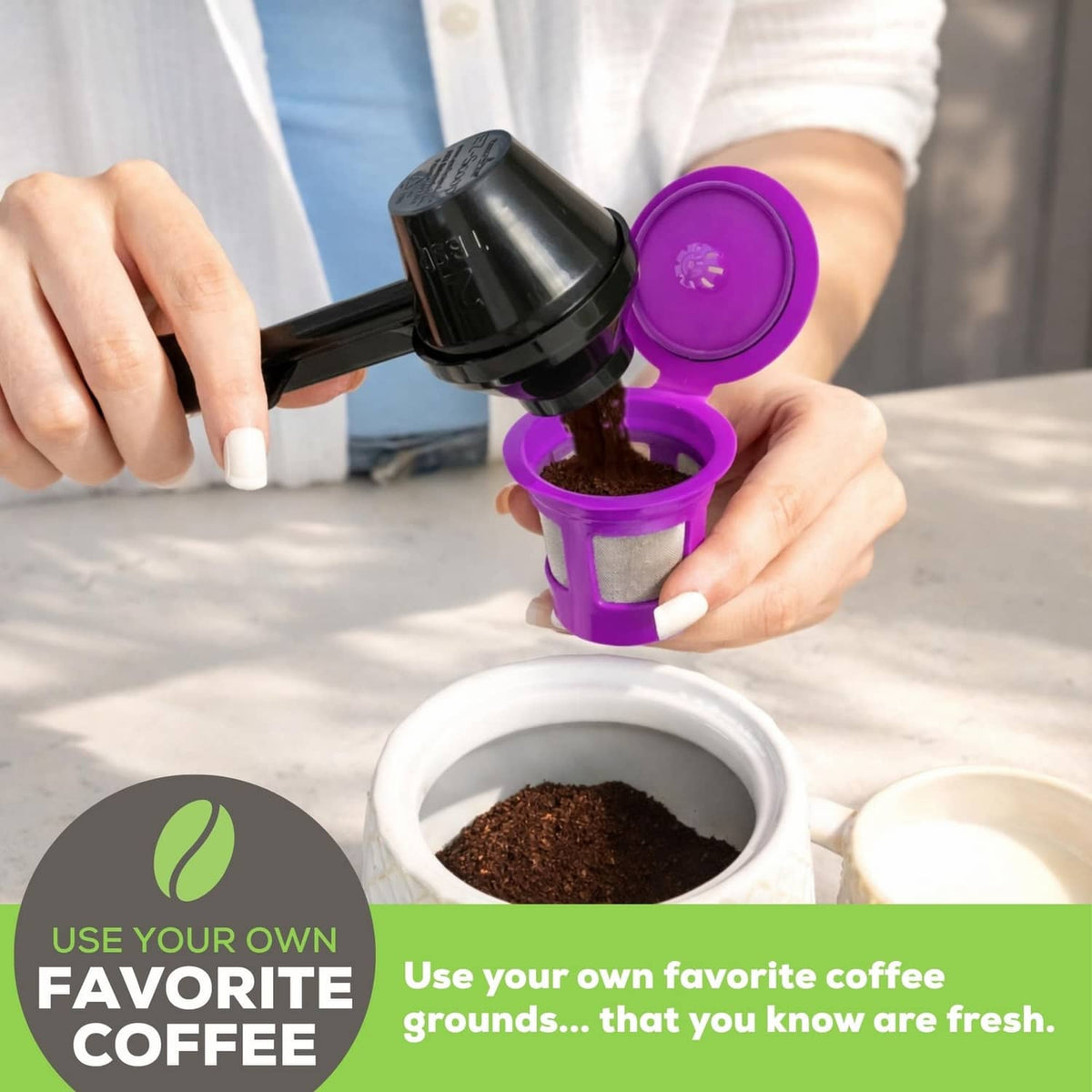 Hands filling a purple reusable coffee pod with ground coffee using a black scoop