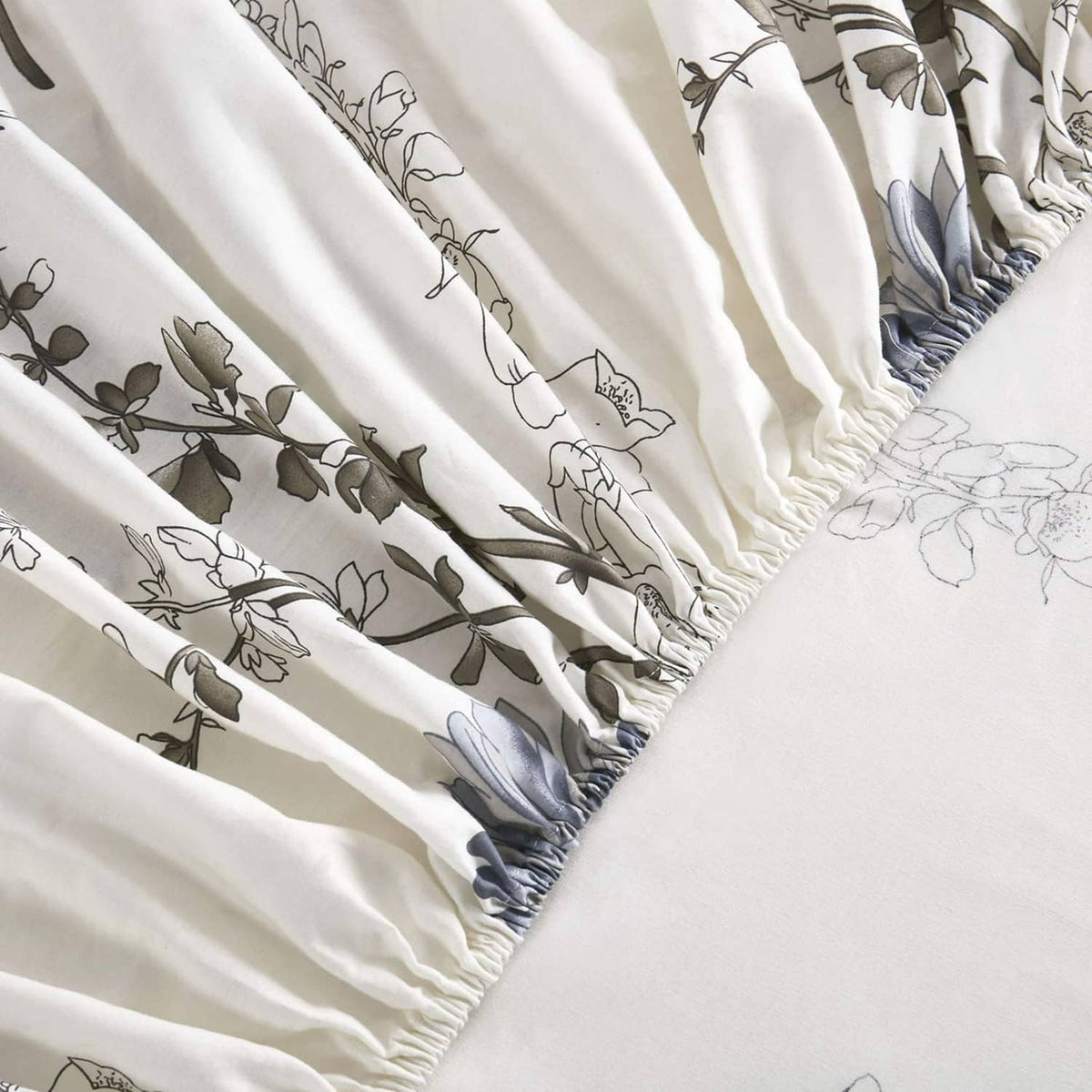 White bed sheet fabric with gathered edge and blue floral botanical linework
