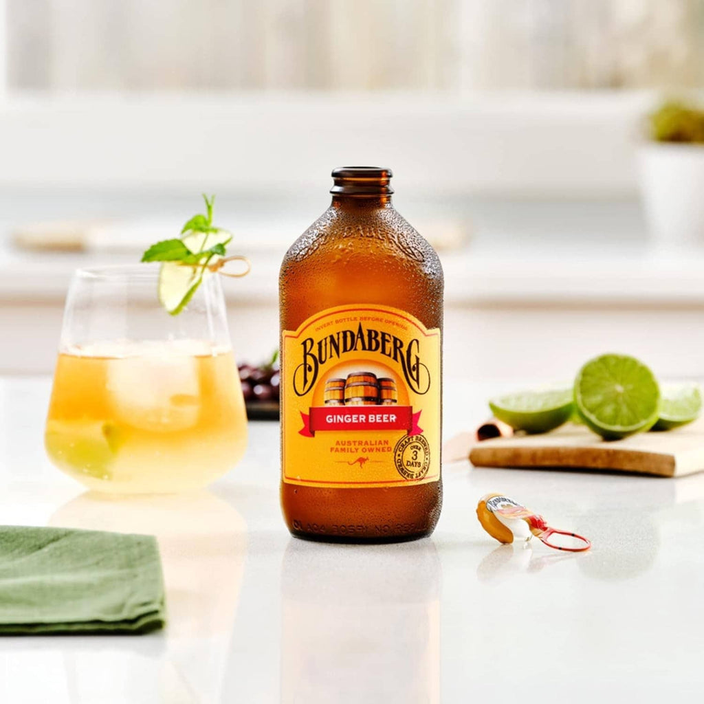 Bundaberg Ginger Beer bottle with glass of amber drink and lime slices