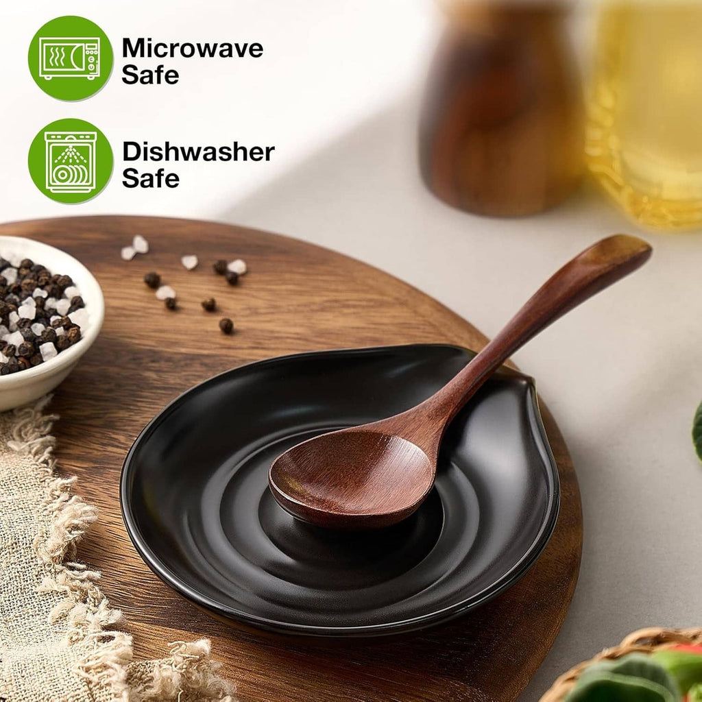 Black ceramic spoon rest with swirl design and wooden spoon resting on top