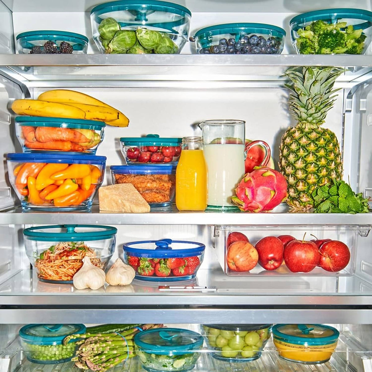 Set of clear glass storage containers with dark green silicone lids in refrigerator