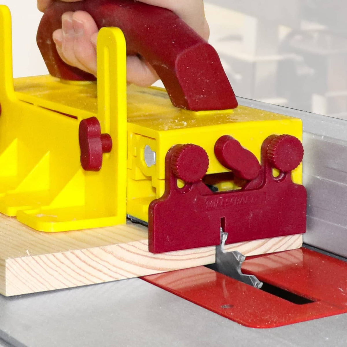 Yellow push block with maroon finger guard and red anti-kickback pads on wood
