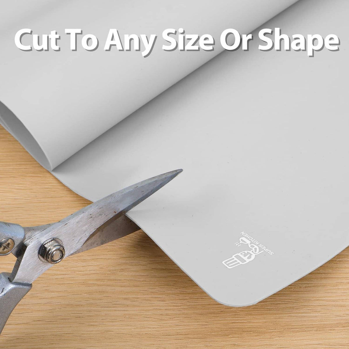 Gray silicone mat being cut with scissors, flexible sheet for custom shapes