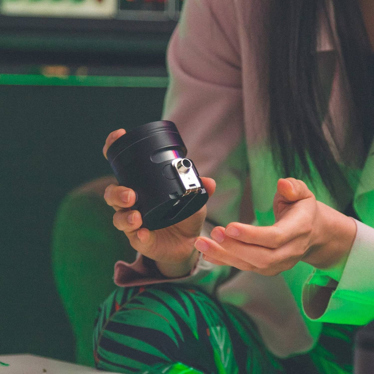 Black portable auto grinder dispenser held in hands with glowing LED window
