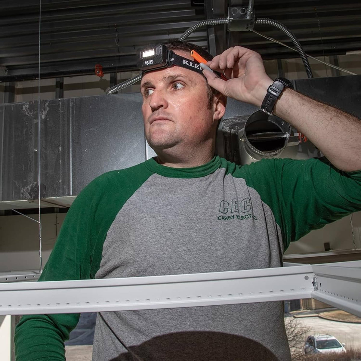 Worker adjusting rechargeable LED headlamp on head with gloved black band