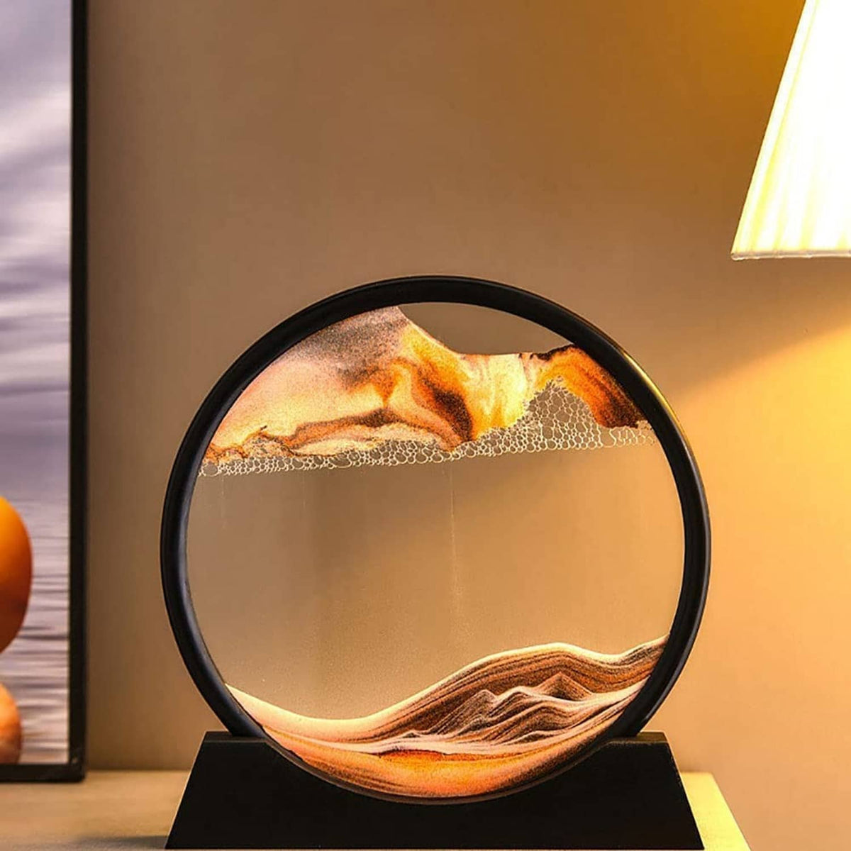 Dynamic sand art sphere with black frame and warm orange dunes on black stand