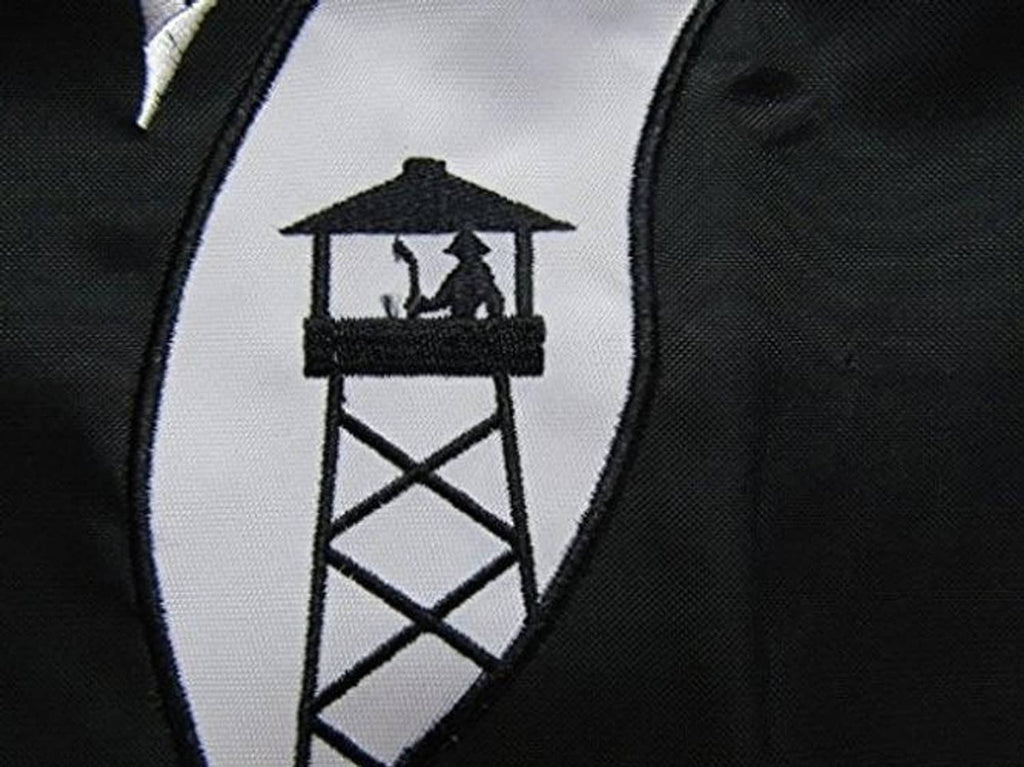 Close-up of embroidered POW*MIA banner emblem with white building icon on black