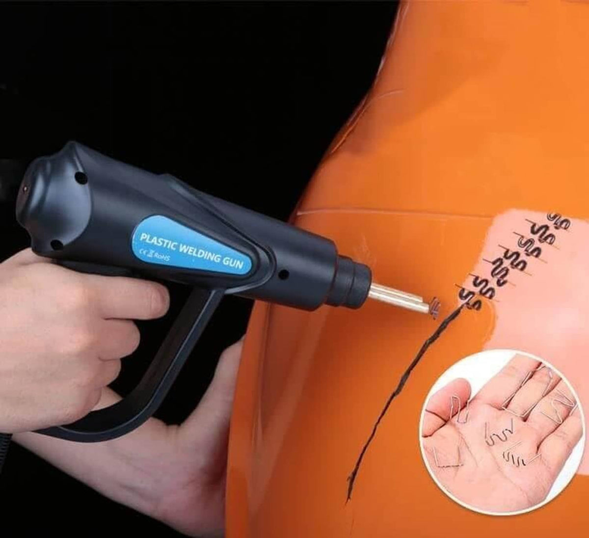 Plastic welding gun applying staples on an orange plastic panel