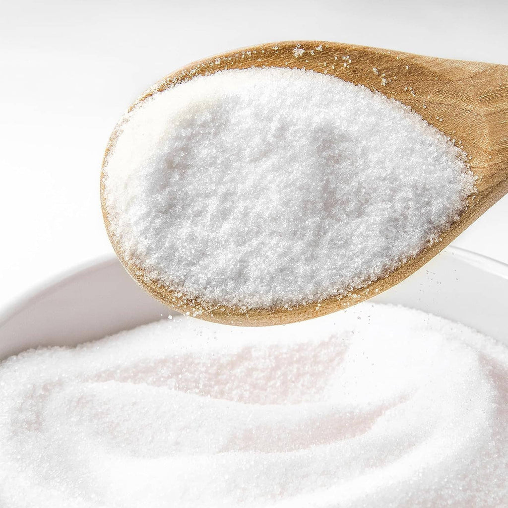 Potassium bicarbonate powder on wooden spoon, fine white granules