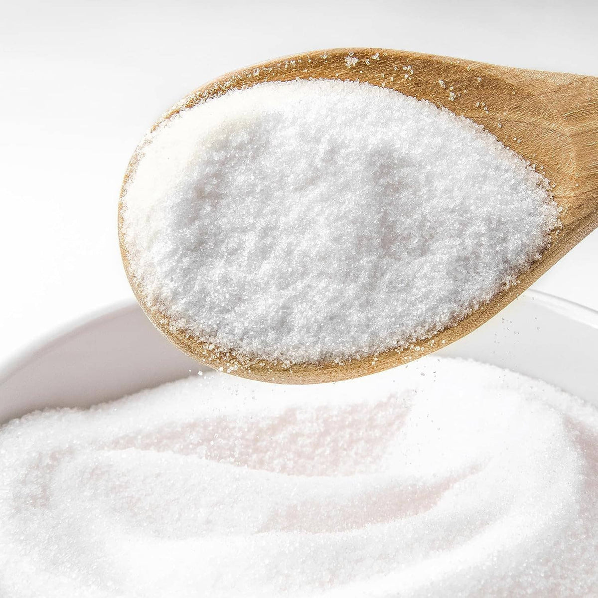 Potassium bicarbonate powder on wooden spoon, fine white granules