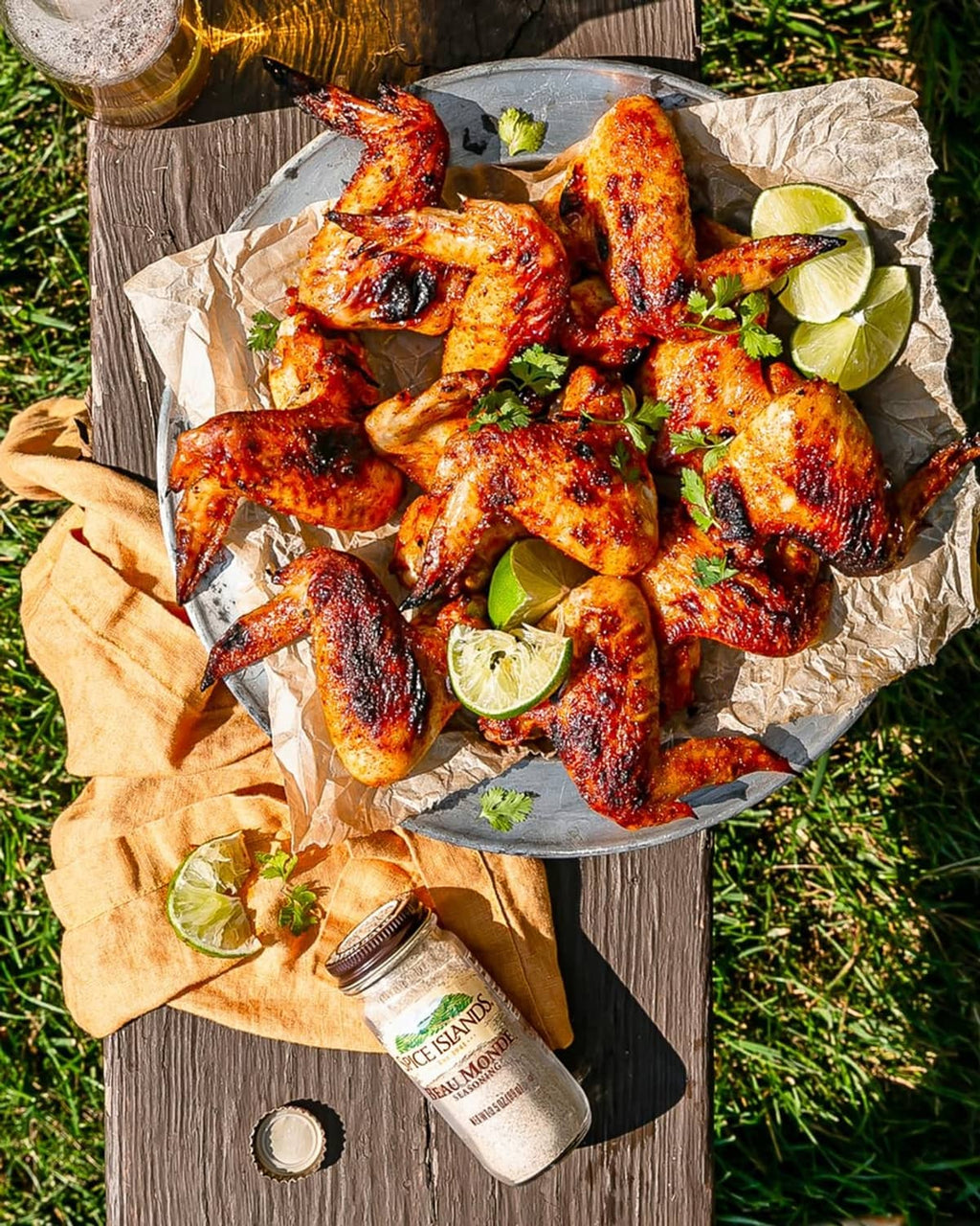 Seasoned chicken wings in a serving tray with lime wedges and herb garnish