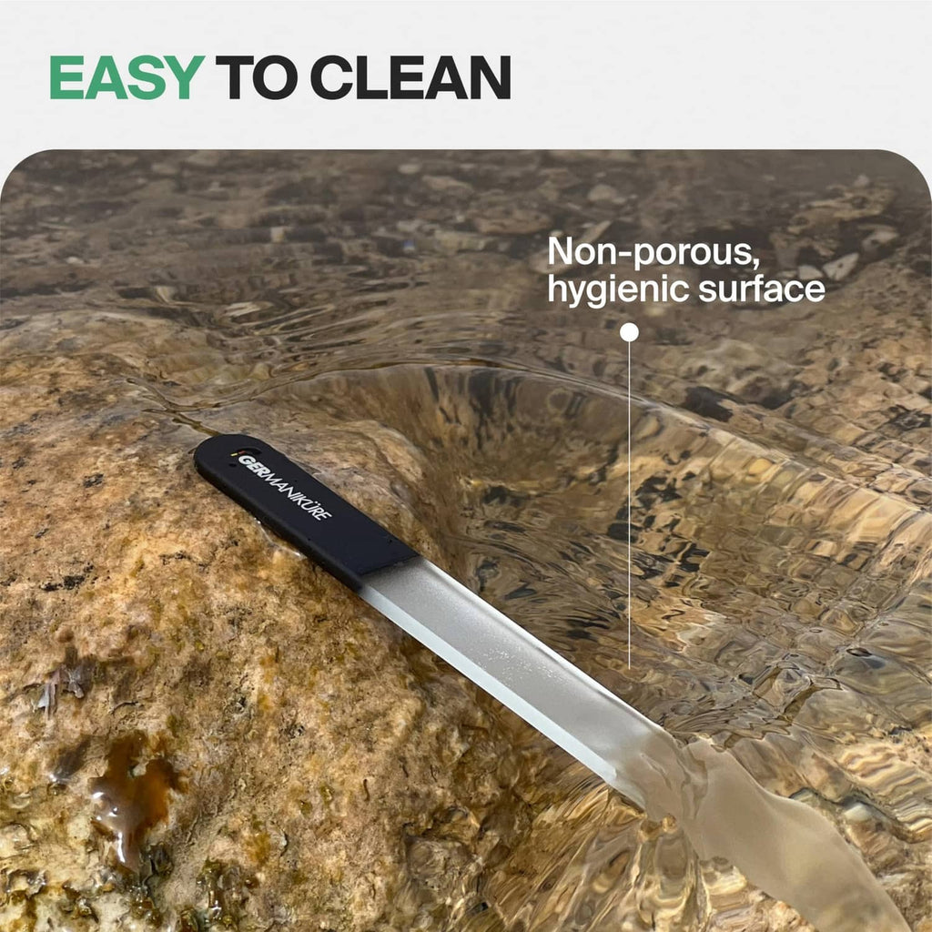Gray glass nail file with black suede sleeve on textured stone surface