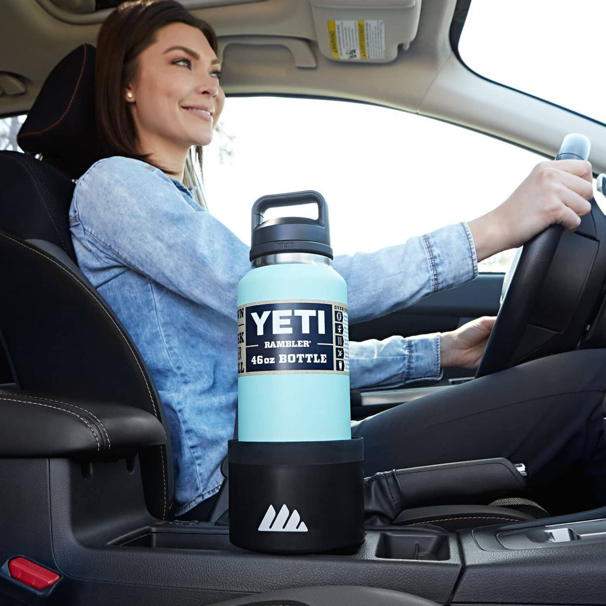 Black cup holder expander in a car holding a light blue bottle