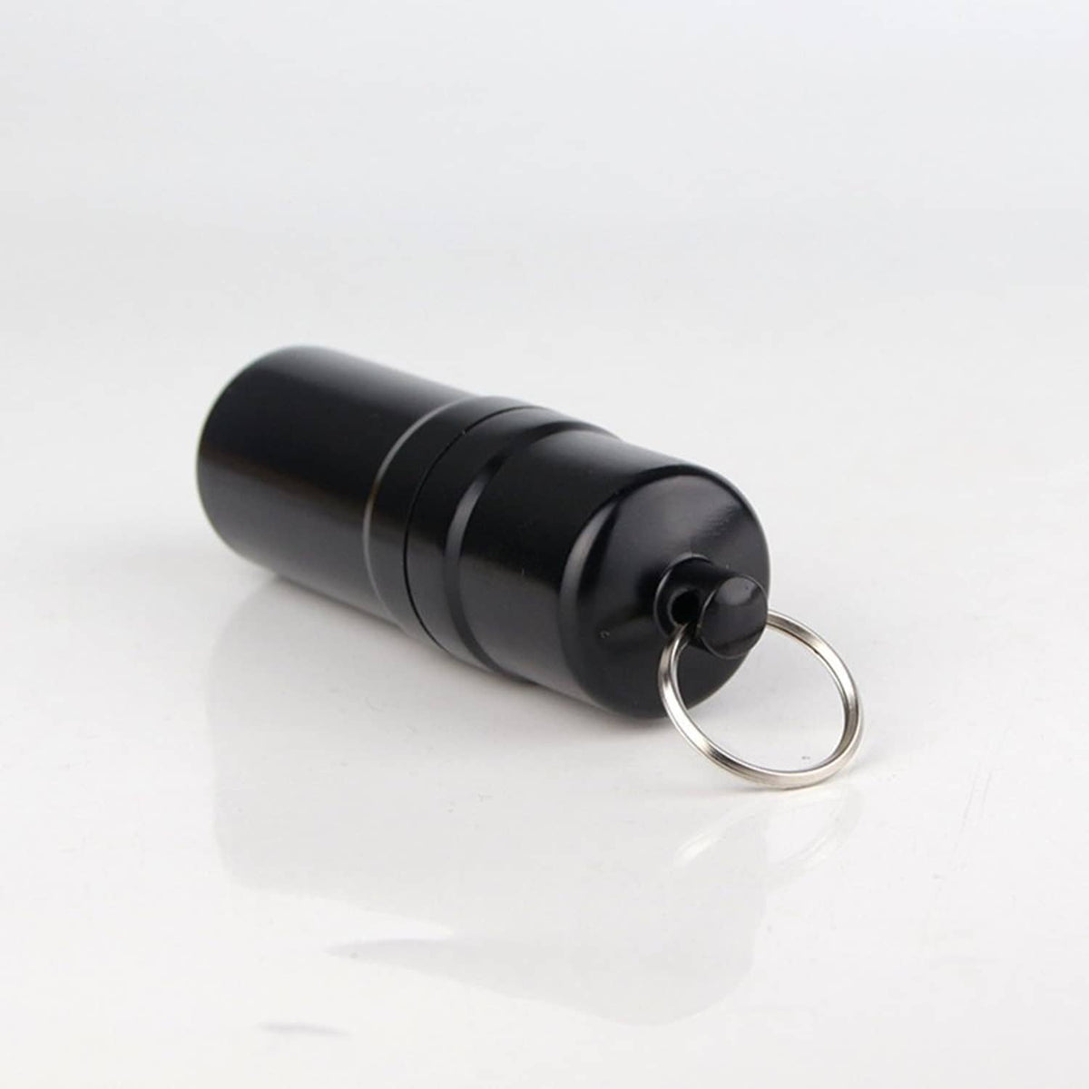 Side view of black round cigarette case with attached metal key ring