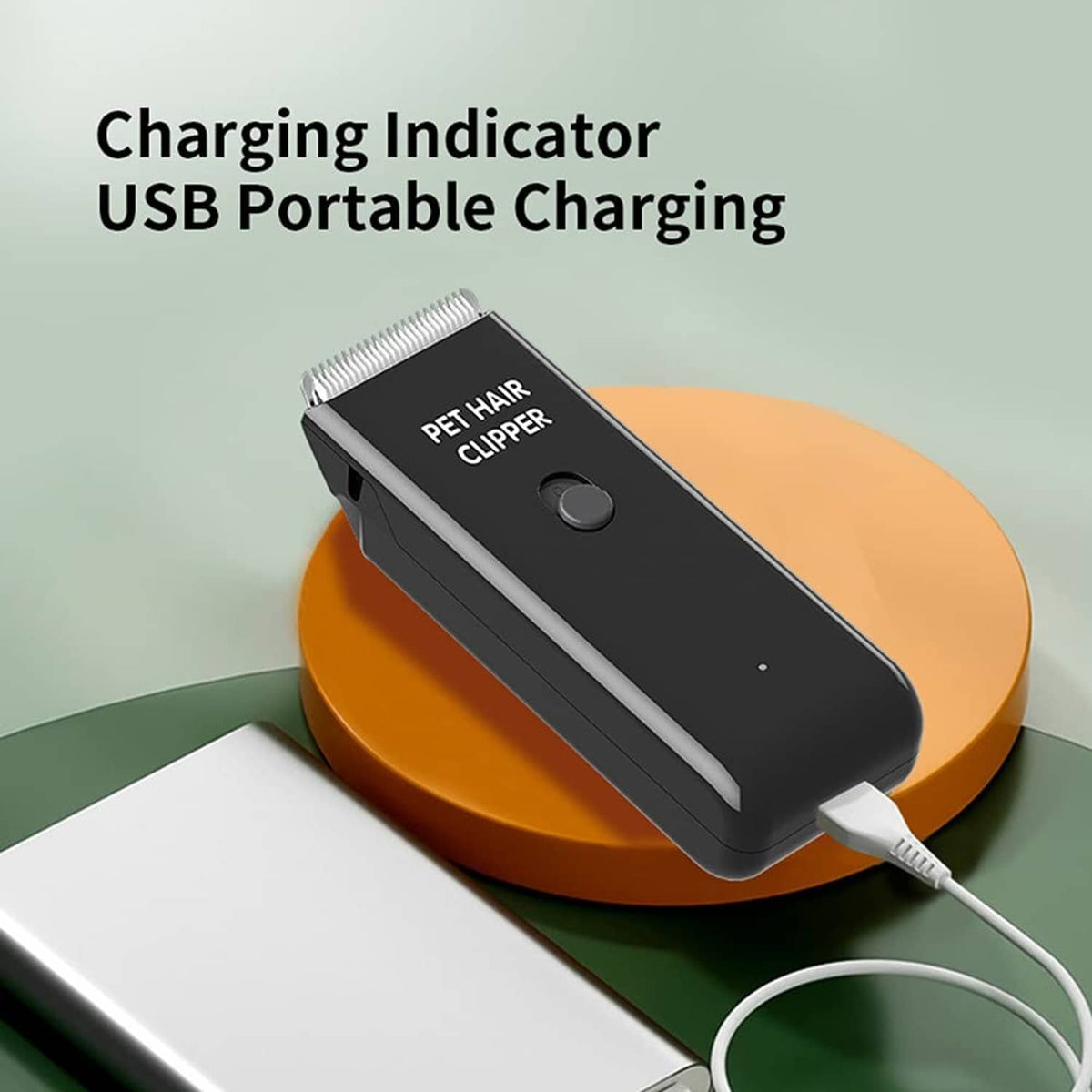 Black pet hair clipper on orange charging base with USB cable