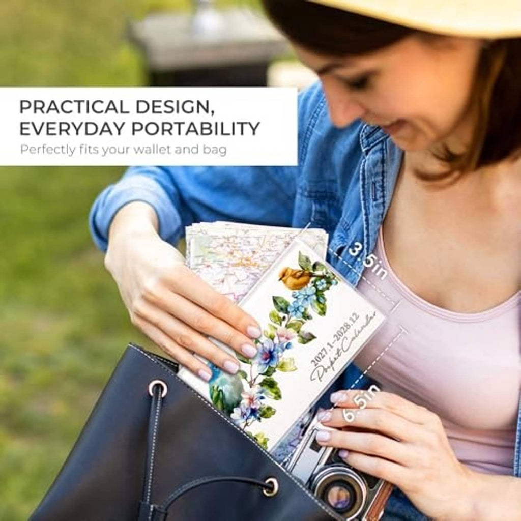 Pocket calendar booklet with bird-flower cover held while reaching for a bag