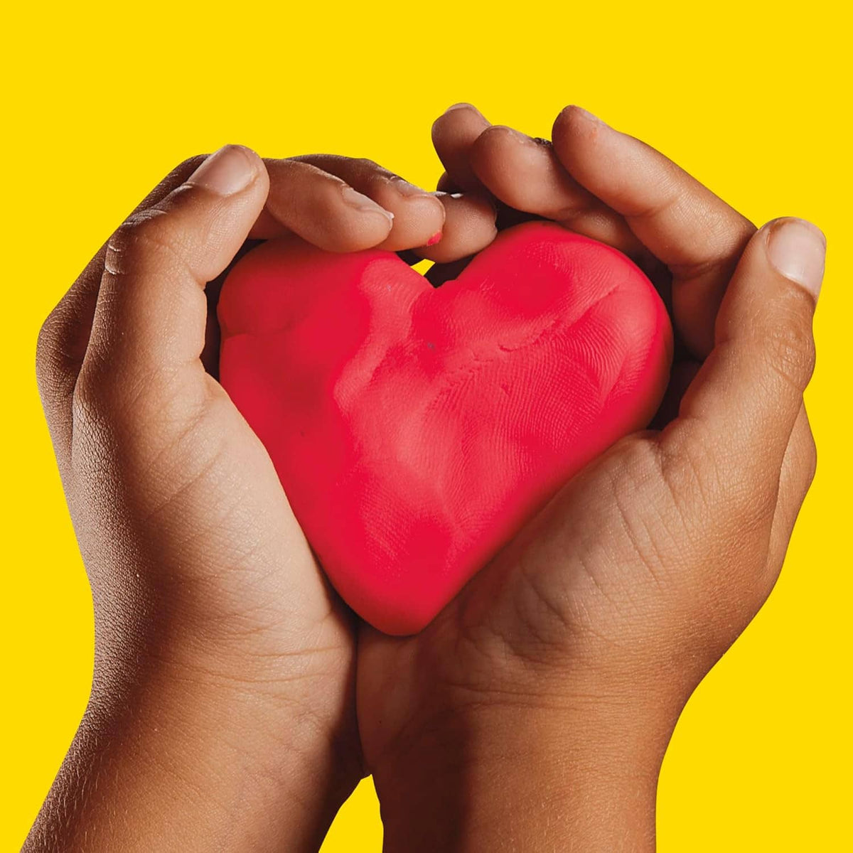 Hands holding a red heart-shaped Play-Doh modeling compound piece