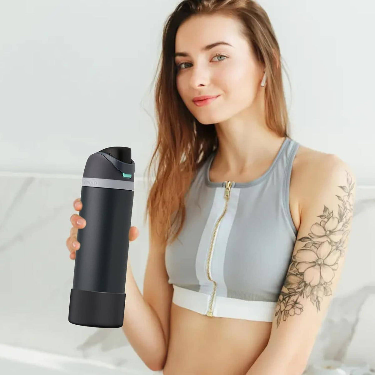 Woman holding a water bottle wearing a black silicone boot sleeve