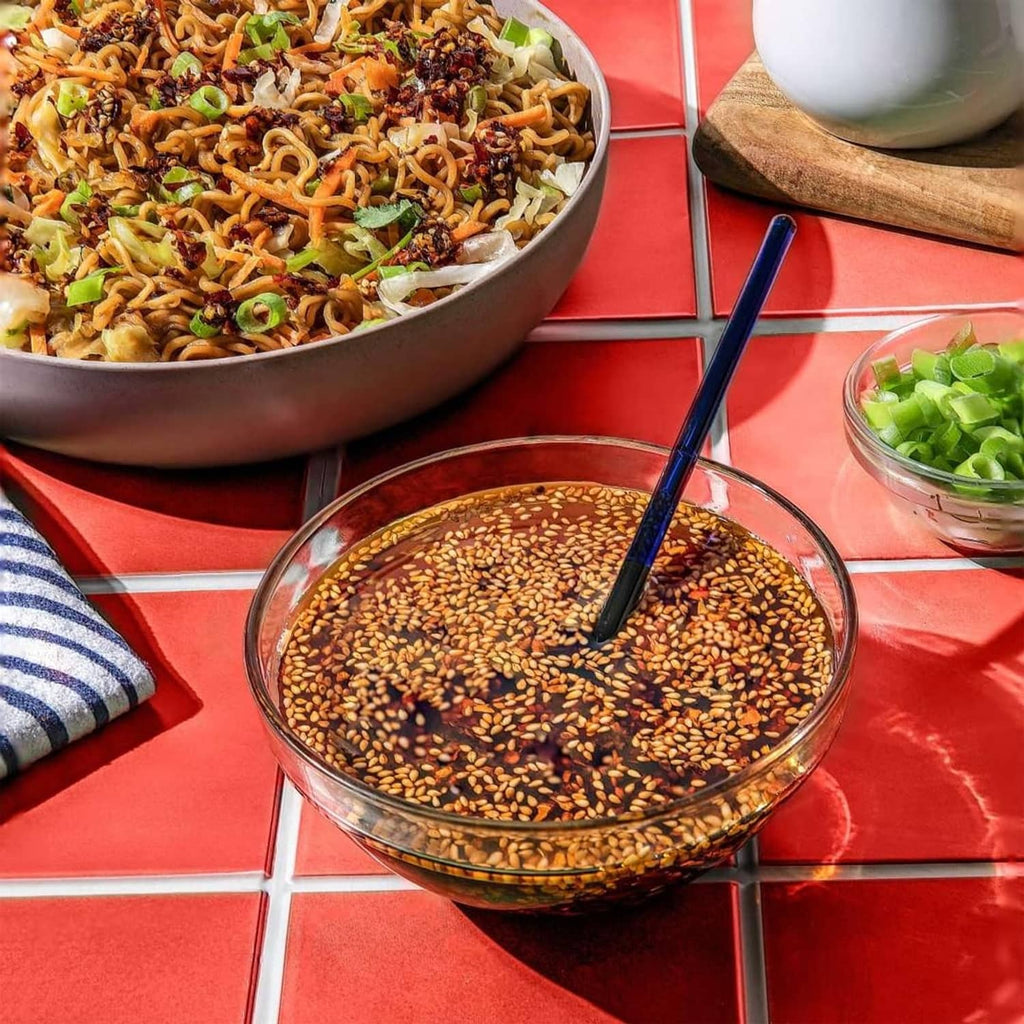 Teriyaki beef yakisoba noodles in pan bowl with chopsticks and sesame sauce