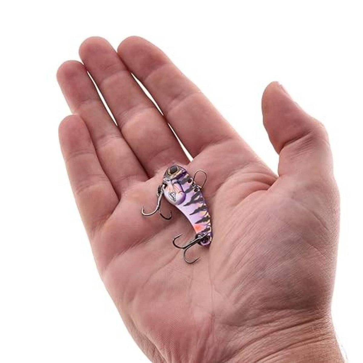Small multicolor blade bait lure held in palm, with black stripes and red eye