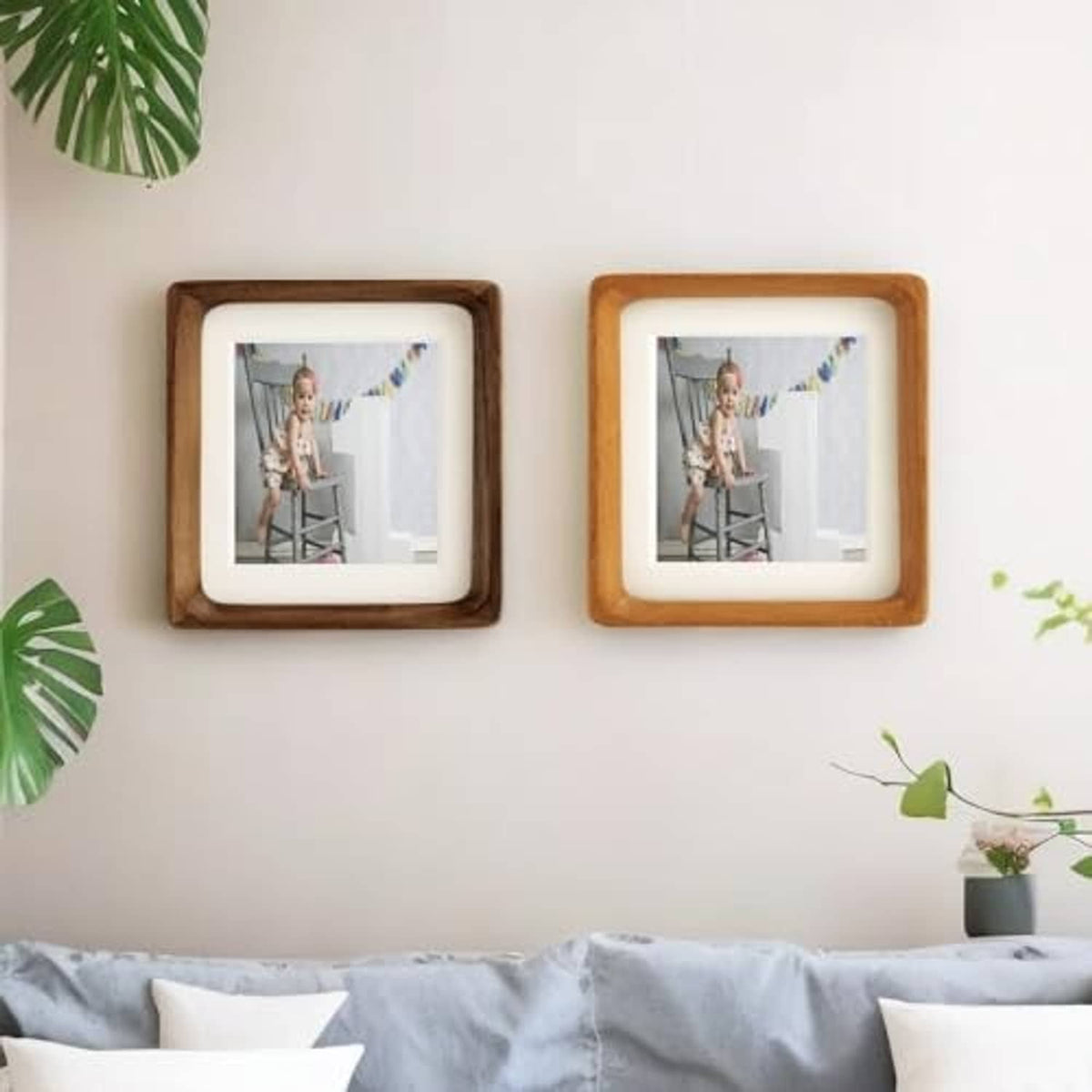 Pair of teak wood picture frames with white mats displayed on a wall