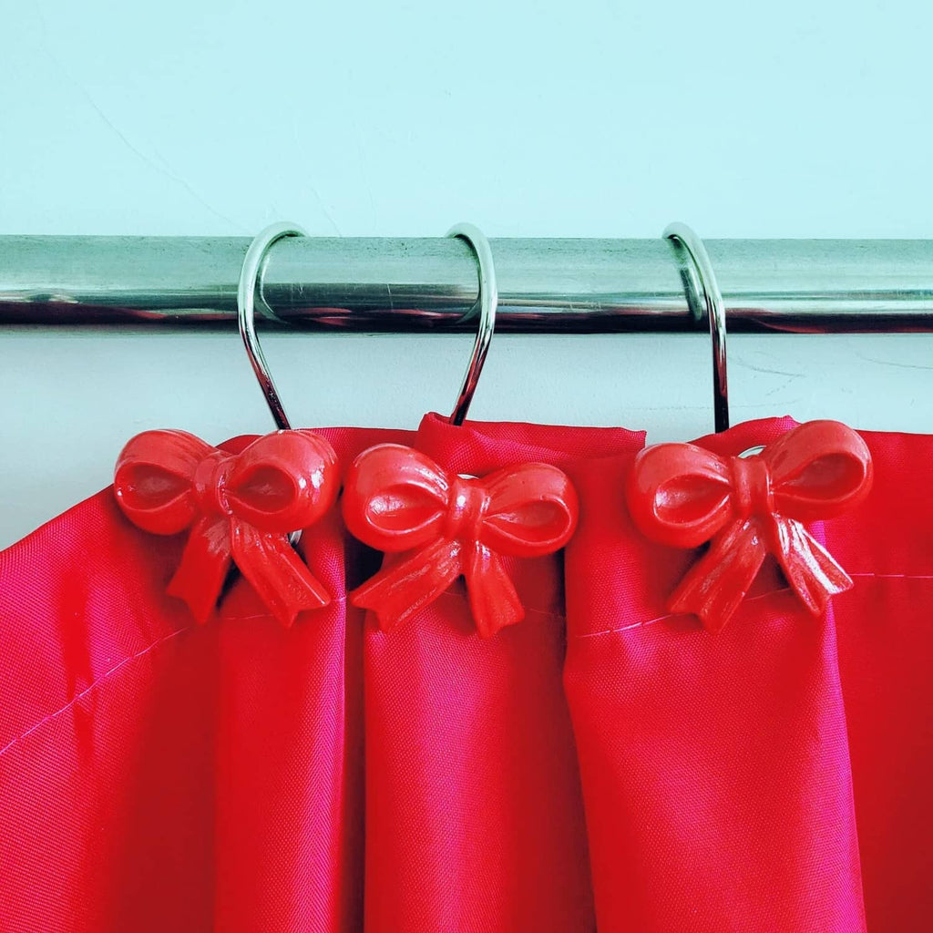 Red shower curtain top with multiple bow-tied fabric loops on metal rings