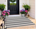Rectangular black-and-white striped outdoor rug with tightly woven, flat stripes.
