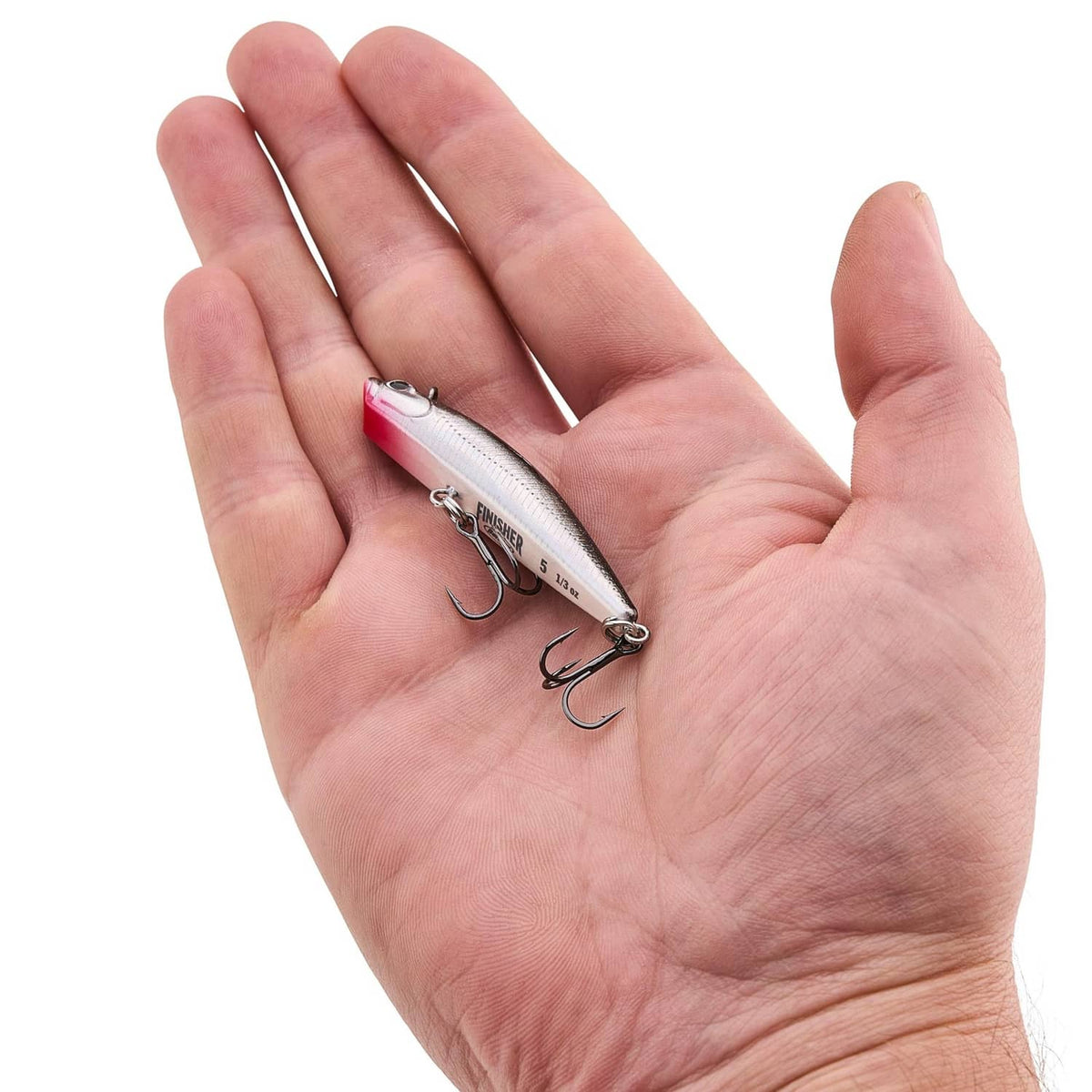 Fishing lure resting in hand, red-and-silver minnow body with treble hooks