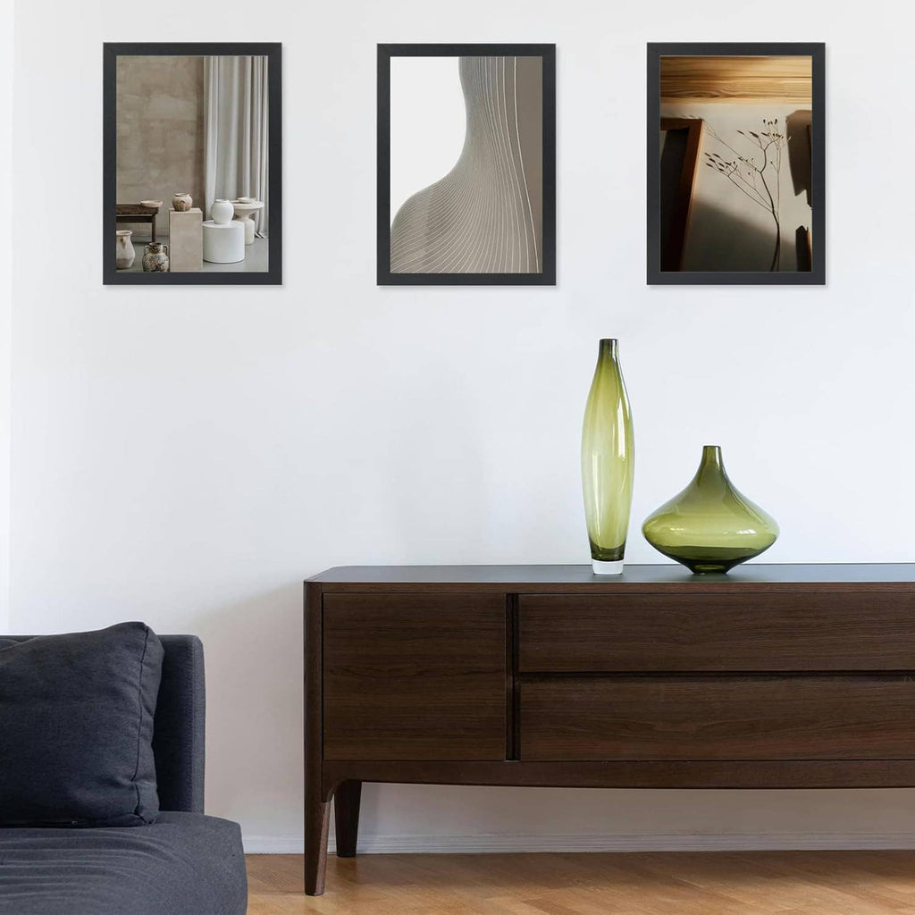 Black 10x15 picture frames on a white wall with a table below and decorative bottles.