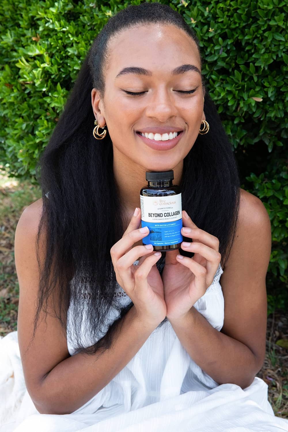 Woman holding a collagen supplement bottle close to her face