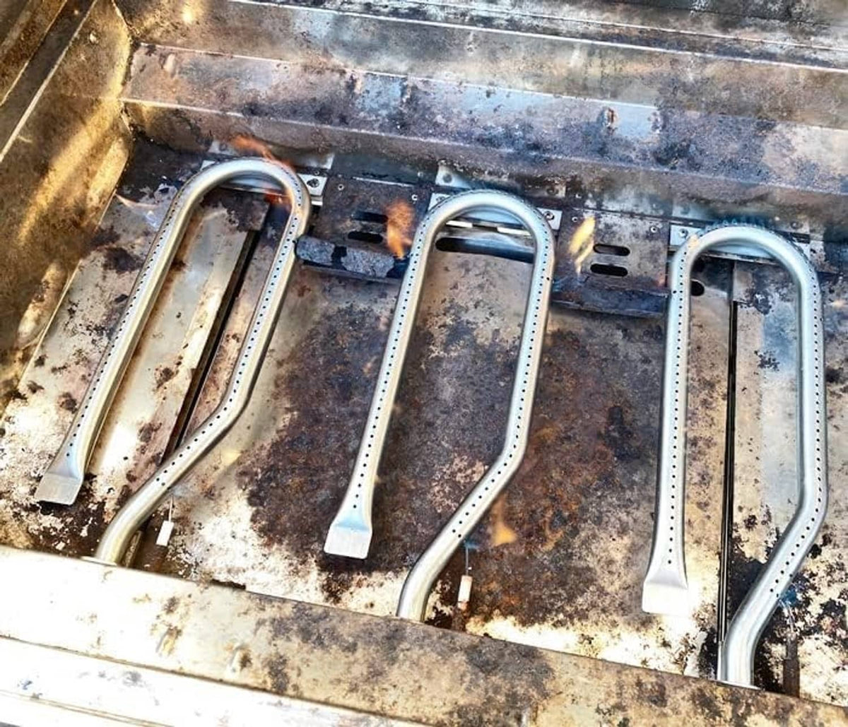Gas grill burners installed in a firebox, U-shaped stainless tubes with mounting bases